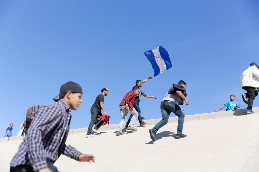 Students walking uphill a concrete hill, holding a blue flag.