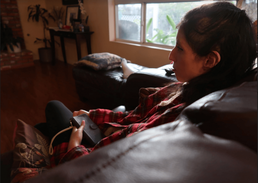 Girl is sitting on a couch with her foot resting on the couch, observing the wall