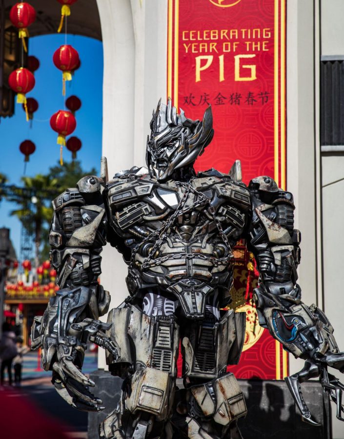 A Mandarin speaking Transformer poses in front of the plaza greeting guests. 