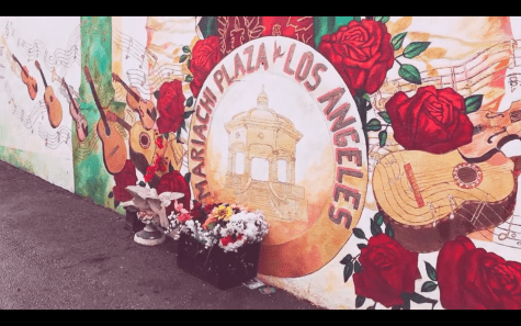 A box of flowers placed in front of a mural at Mariachi Plaza, Los Angeles.