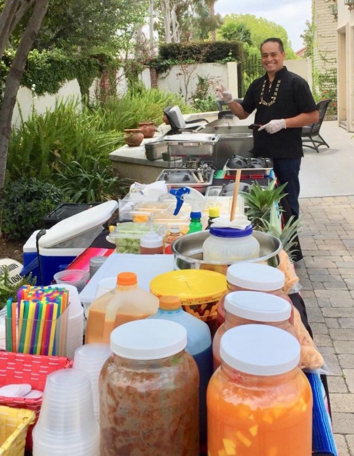 A portrait of Oscar Hernandez catering a party with items such as tacos, corn and fruit.