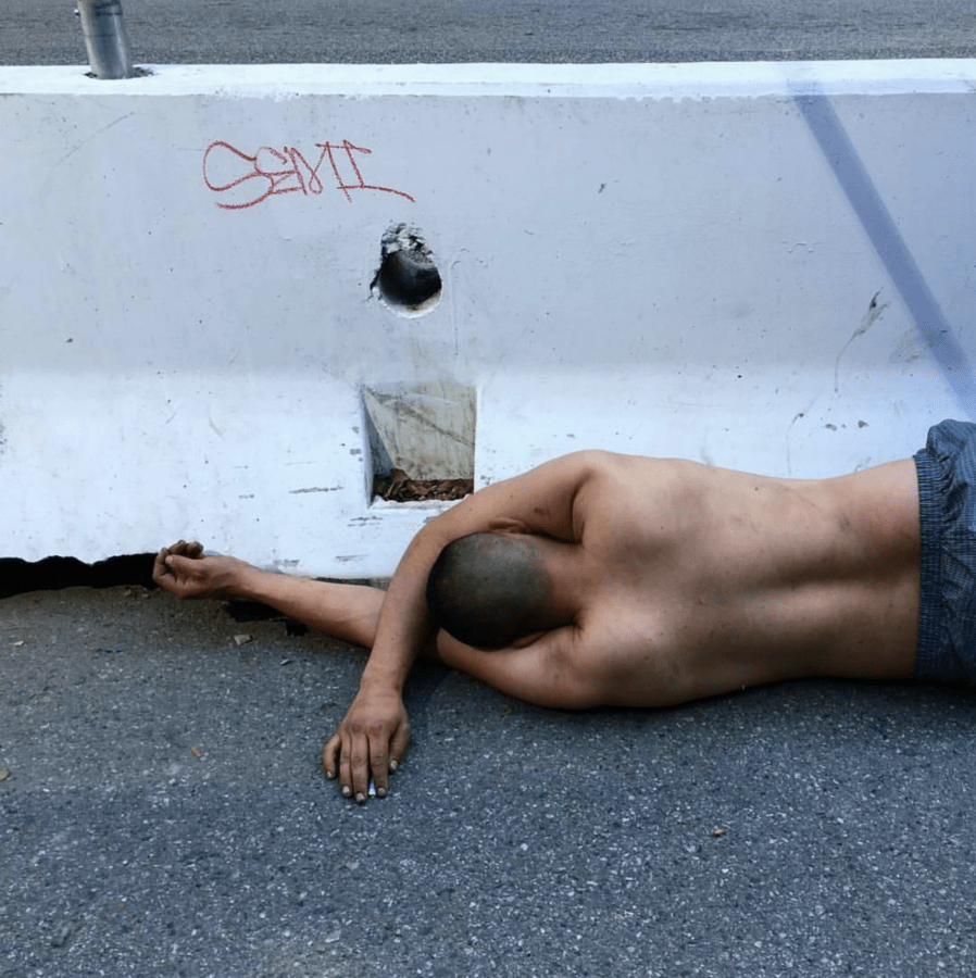 Picture of a man laying on his side belly, facing a wall of concrete.