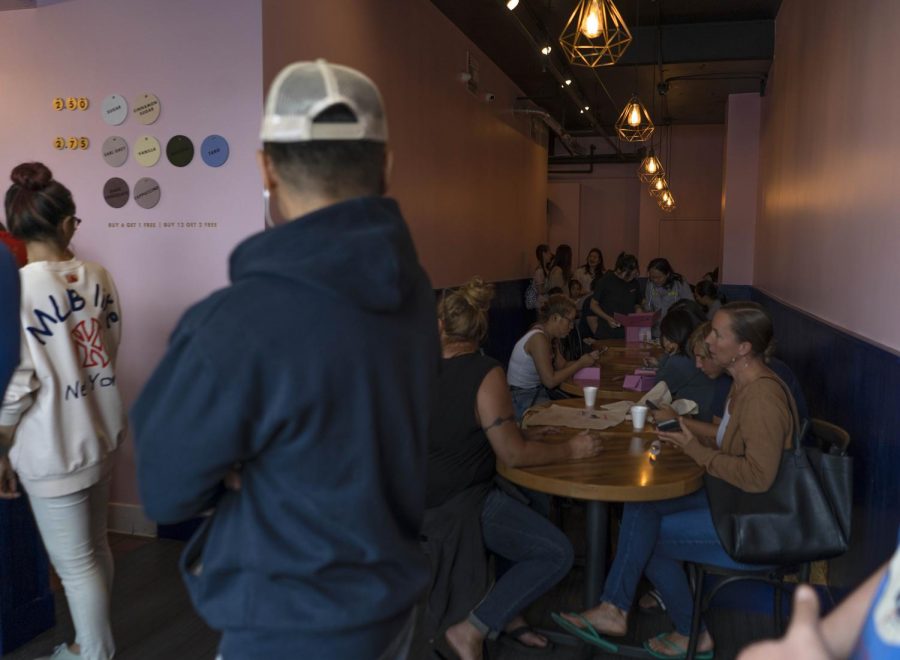 In the midst of Dot & Dough Doughnut_s grand opening, patrons relax and enjoy their free doughnuts last Saturday