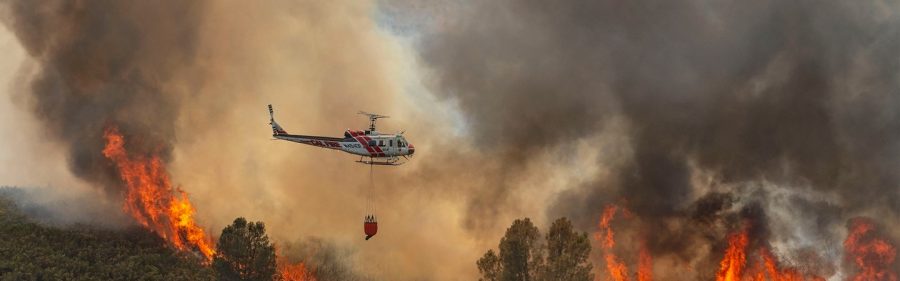 A Cal Fire helicopter flies above a fire.
