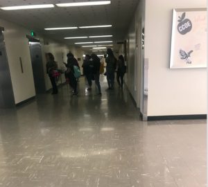 Half a dozen students and others are shown waiting for an elevator in King Hall.