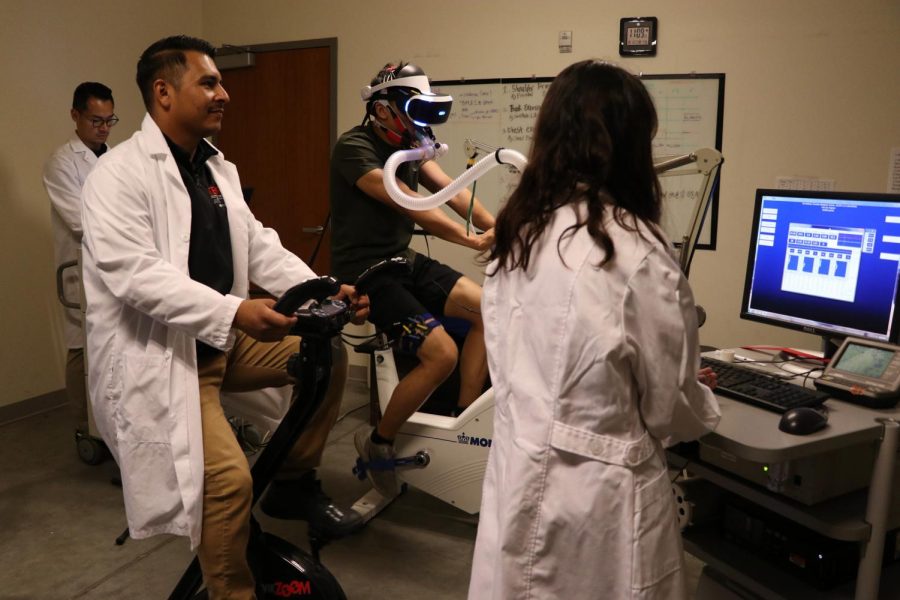 Axel Munoz (left) follows along with the movements of the research participant as he goes through a virtual reality bike ride.