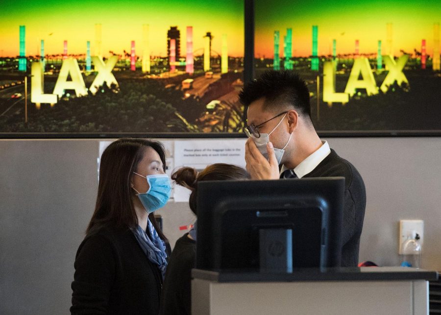 Airline check-in staff at LAX airport wear a face mask to protect themselves from the coronavirus.