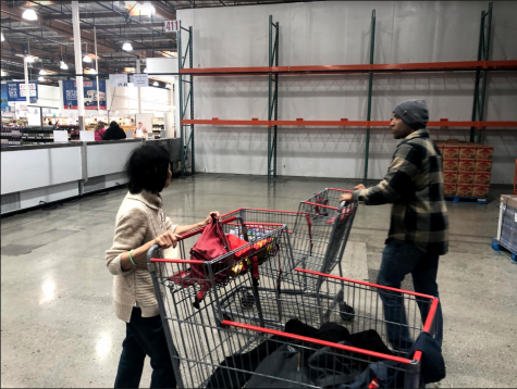 Shoppers walk past empty shelves at Costco. By Vanessa Wyatt.