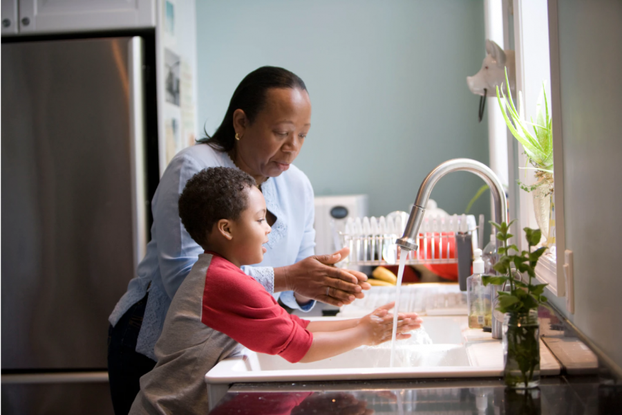 A+mother+teaches+her+son+how+to+properly+wash+his+hands+at+their+kitchen+sink.+She+has+him+briskly+rub+his+soapy+hands+together+under+fresh+running+tap+water%2C+to+remove+contaminants%2C+which+reduces+the+spread+of+pathogens.+%28Photo+courtesy+of+the+CDC%29