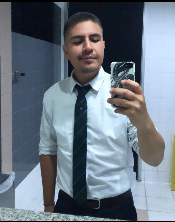 A selfie in a mirror of Marcos Licon wearing a black tie and white shirt.