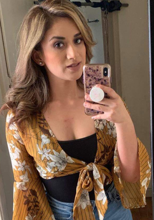 Headshot of Sandy Solavei taking a selfie with her phone and wearing a tie-in-front top.