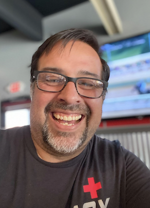 A headshot of Jaime Brown with glasses and a goatie, smiling.