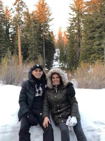 Mother and son pose in snowy background wearing winter coats.