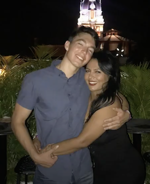 A shot of two people hugging and posing outside at night time.