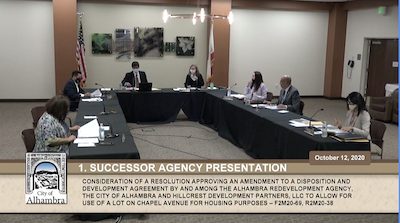 A photo of council members sitting around a long U-shaped table.