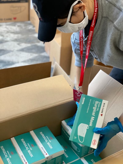 Someone with cap and masks reaches into box