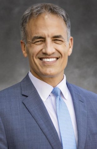 A headshot of a man with a blue suit.