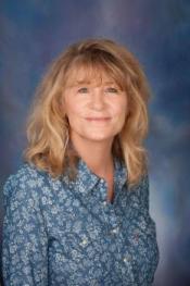 A woman with a blue button down shirt and blond hair.