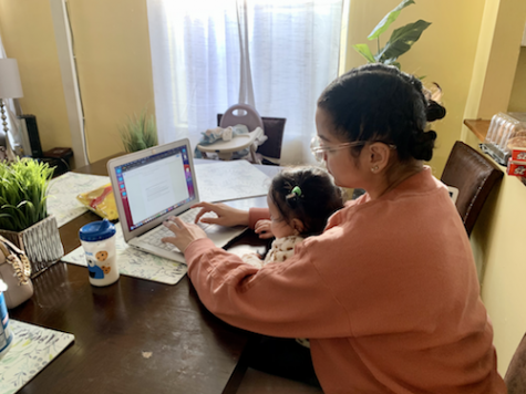 A student at a computer with a child on her lap.