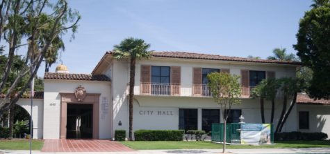 Cream colored building with red rile roof and palm trees in front