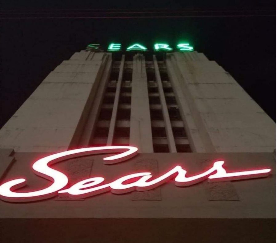 A building with a red, lit up Sears sign in cursive