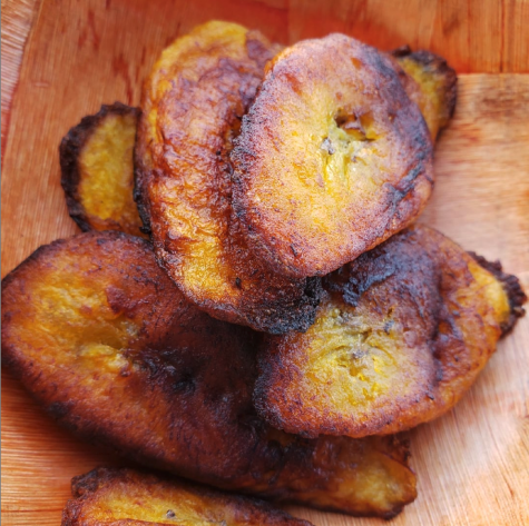 Pan-fried plantains piled on a wooden dish.