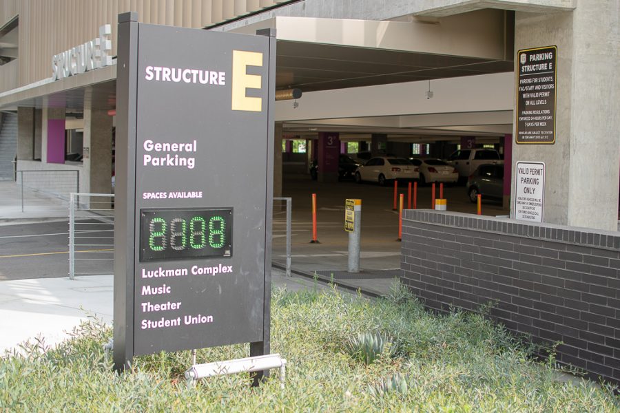 Picture shows the entrance of parking structure E. A sign pictured reads Structure E and displays the number of available parking spaces .