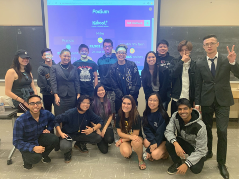 Photo shows members of Alpha Phi Sigma infant of a projector screen in a Cal State LA classroom. 