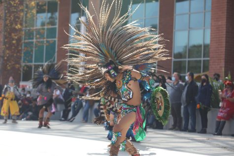Man dancing to music dressed in headwear with feathers.