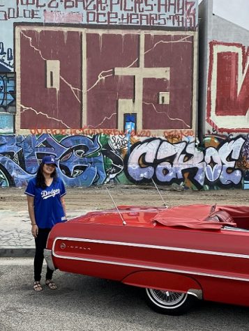 In the photo the girl with blue t-shirt and blue cap standing near the red big car.