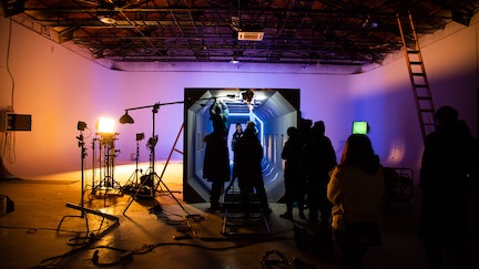 Purple and pink lights on set and profile of film set workers