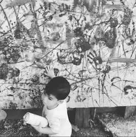 Black and white photo of art in the background and a small child in the foreground