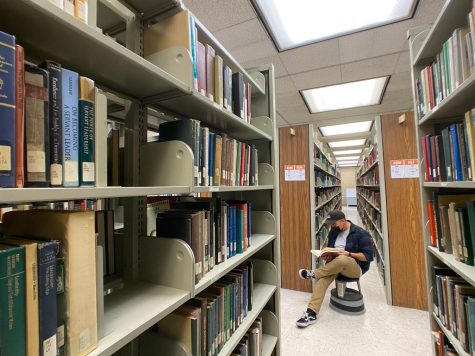 shelves of books on either side and a student sitting in the middle