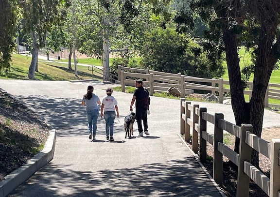 A family walking their dog through the dog park
