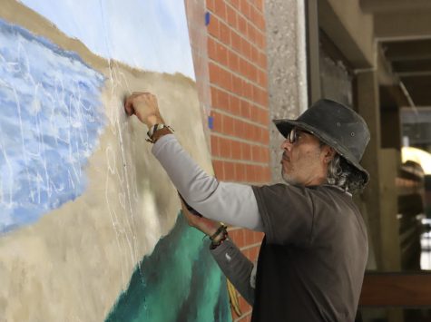 Artist Claudio Talavera-Ballon painting the first part of a mural in front of the Cal State LA library.