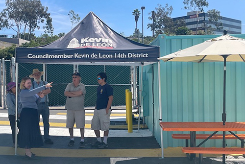 A navy tent with several people talking under it.