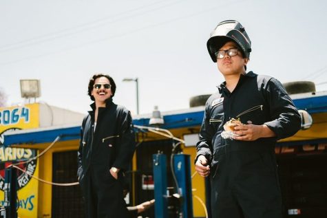 Two guys wearing black uniforms outside in daytime