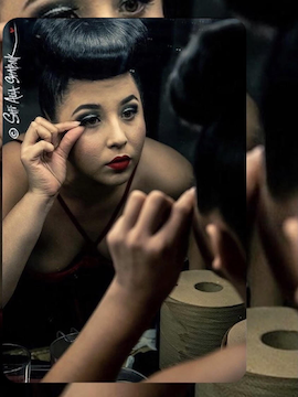 Loretta E. doing her makeup while looking into a mirror.