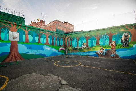 Playground Mural Renovation that depicts two tourists in the midst of forest, next to a river, and surrounded by animals