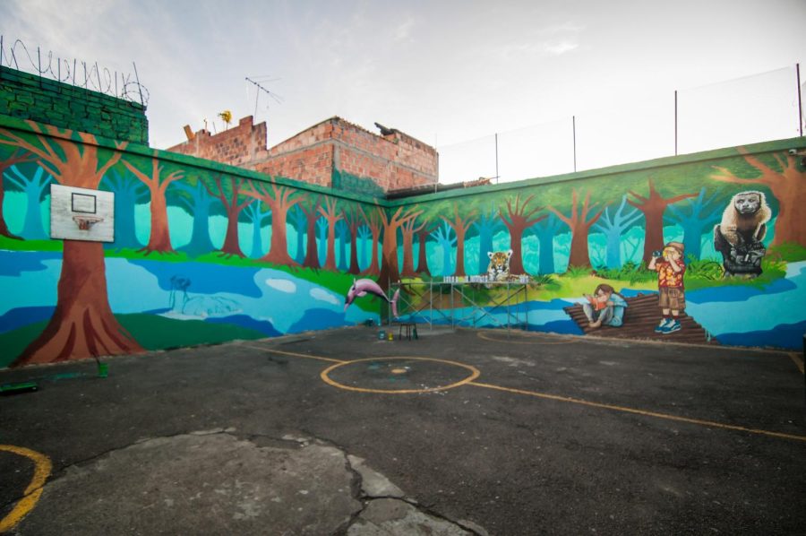 Playground+Mural+Renovation+that+depicts+two+tourists+in+the+midst+of+forest%2C+next+to+a+river%2C+and+surrounded+by+animals