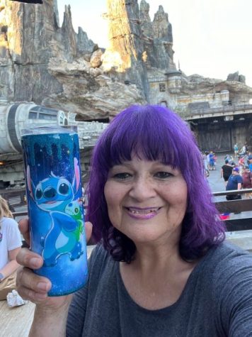 person with purple hair and blue cup at Disney theme park