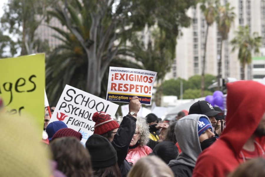 Strike attendee holds up sign amid several thousand supporters during the first rally of the action. Sign translates to We keep schools safe, We Demand Respect. Photo by Erik Adams.