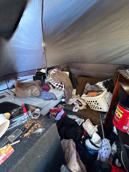 Items such as white laundry basket, clothing, slipper coffee, and other items inside a tent.