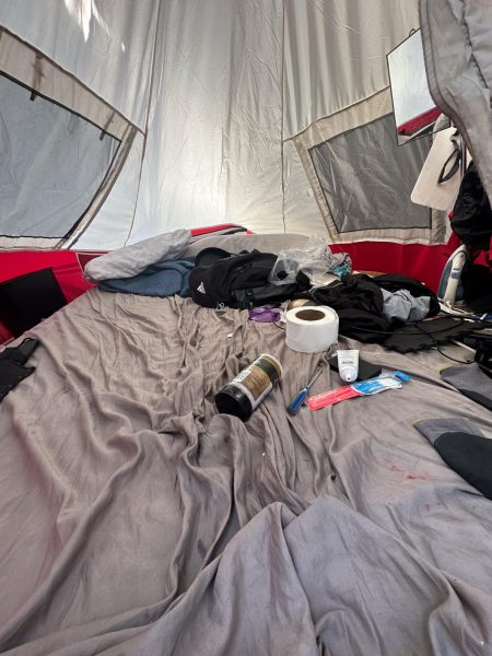 Beige sheet with items like toilet paper on it in a tent