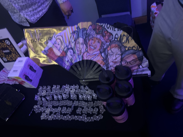 A table with a hand-fan, trinkets and souvenir cups. 