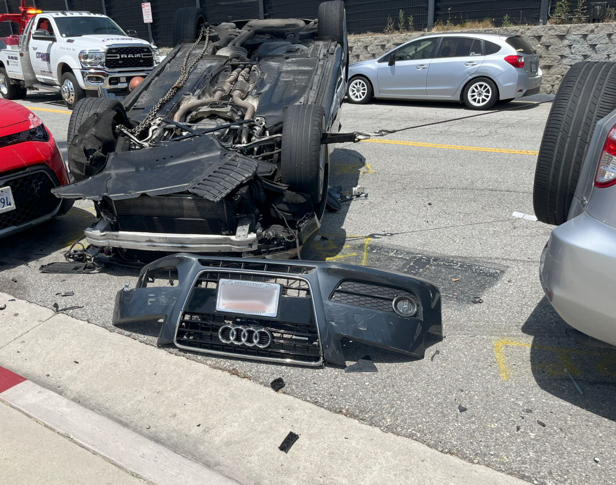 The bumper of the flipped over car fallen off of the vehicle. 