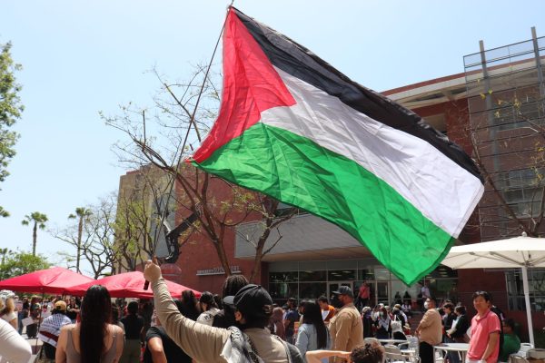 Protester waves a Palestinian flag in front of the University Bookstore during a May Day for Palestine rally on May 1, 2024. The event was organized by the Cal State LA Students for Justice in Palestine. 