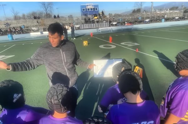 A high school coach giving high school students encouragement during football practice.