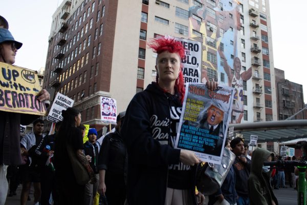 Protesters march past a mural on a nearby apartment building near Pershing Square during the "We Fight Back" protest in downtown L.A. on Monday, Jan. 20.