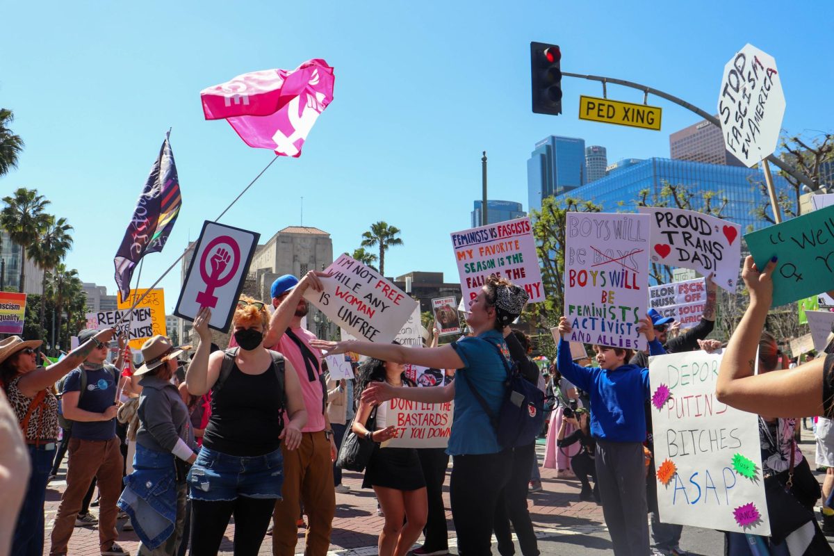 Los Angeles Women's March protestors dance with their signs and wave their flags at City Hall on Saturday, March 8, 2025 in Downtown L.A.